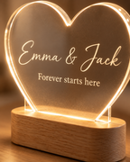 Close-up of the engraved names, LED-lit acrylic edge and oak wood base of the Heart Glow lamp