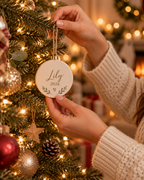 Hand holding the personalized ceramic ornament by its jute string to show its size