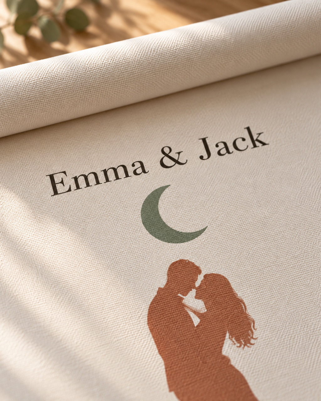 Close-up of the names, green moon and couple silhouette on the personalized canvas texture