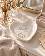 Personalized heart trinket tray holding gold rings and a necklace on a bedroom dresser