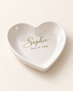 Personalized ceramic heart trinket tray with gold name and date on a plain cream background
