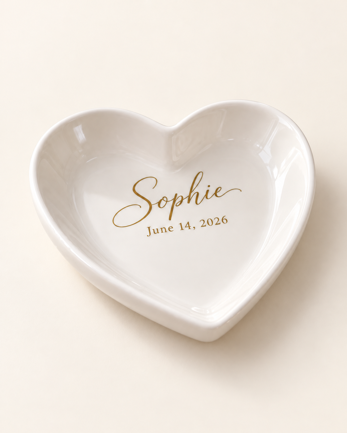 Personalized ceramic heart trinket tray with gold name and date on a plain cream background